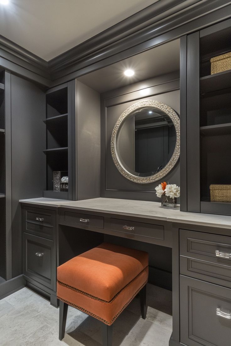 an orange ottoman sits in front of a gray dressing room with built - in shelving