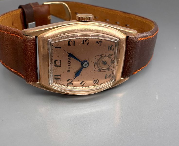 Rare 1940s original BULOVA CURVEX TANK with brand new brown saddle leather strap and with a very well preserved Curvex glass, with sought-after, salmon-colored original dial with black, Arabic indexes and original, blued steel pointers. Original legendary BULOVA caliber 10BC with 15 jewels, watch runs perfectly for it's age. Worth collecting, original timeless classic in good condition! Vintage Brown Watch With Rectangular Dial, Classic Brown Watch With Waxed Finish, Antique Brown Analog Watch, Vintage Brown Formal Watches, Vintage Leather Watch With Chronometer, Vintage Watches With Leather Strap And Rectangular Dial, Vintage Watch With Leather Strap And Rectangular Dial, Vintage Leather Watches For Business, Vintage Brown Watches With Leather Strap