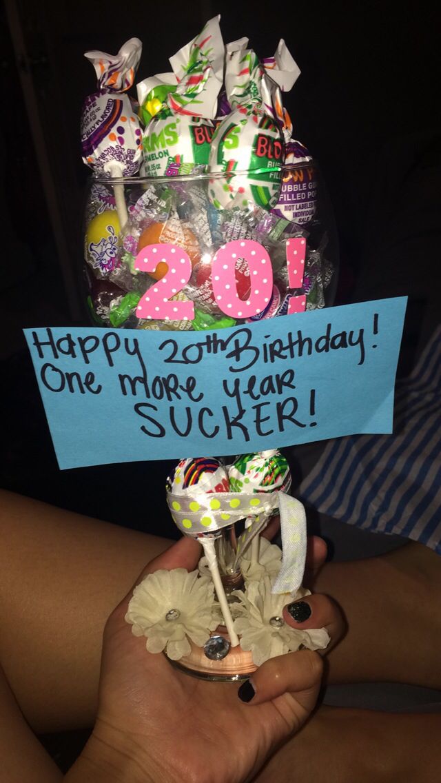 a person holding up a birthday card in front of a vase filled with candies