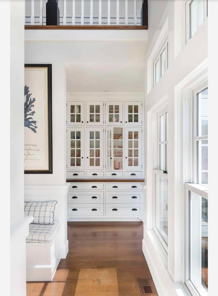 an empty room with white cabinets and wood floors