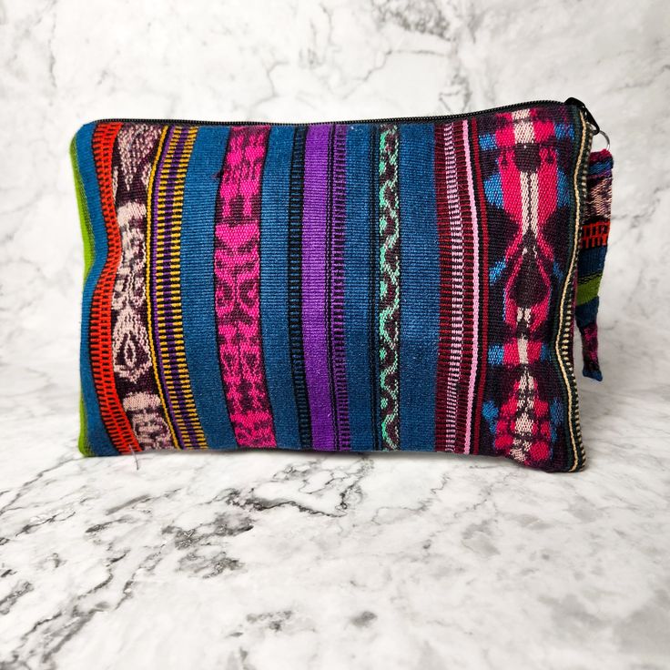 A true work of art, each Corte Cosmetic Bag is lovingly crafted on a traditional pedal loom with the same vibrant fabrics that fashion the iconic skirts of Guatemalan women. This results in an exclusive and one-of-a-kind product that will add a touch of luxury and culture to your collection. Each one has enough space to hold all of your needs, from makeup to brushes to nail polish and more! As always, Handmade and Fair Trade! 9" H x 6" W Brightly lined with nylon Zipper pull-tab 100% cotton Asso Multicolor Handwoven Pouch Bag, Artisan Multicolor Woven Shoulder Bag, Artisan Multicolor Rectangular Shoulder Bag, Bohemian Fabric Travel Bag, Bohemian Travel Bags In Fabric, Artisan Bags With Weaving Work, Artisan Multicolor Handwoven Bag, Multicolor Artisan Handwoven Bag, Multicolor Handwoven Artisan Bag