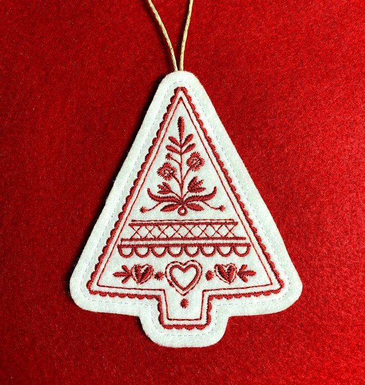 a red and white christmas ornament hanging on a red cloth covered tablecloth