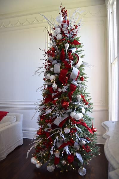 a christmas tree decorated with red, white and silver ornaments is in the corner of a room