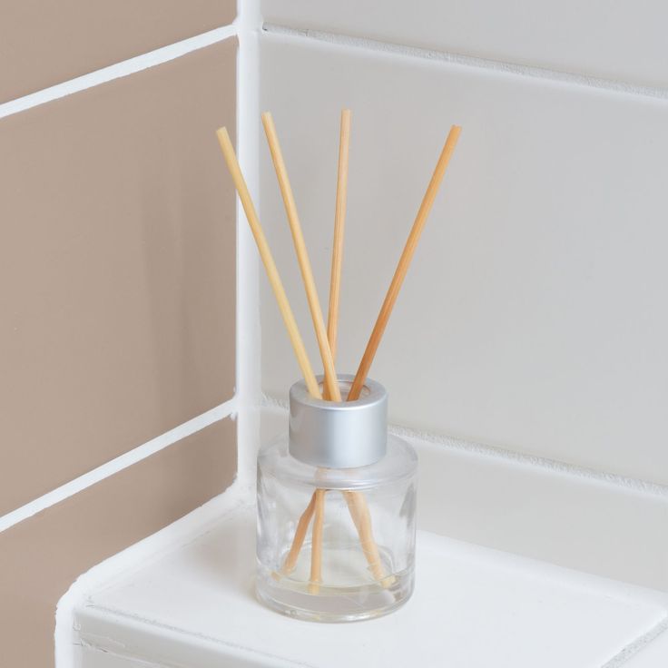 reeds in a glass container on a shelf