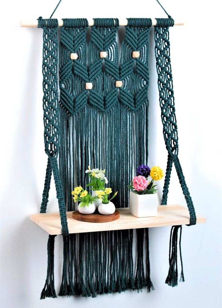 a macrame wall hanging with flowers and potted plants