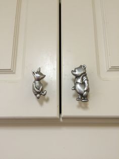 two metal mice sitting on top of a white cabinet door with knobs in the shape of animals