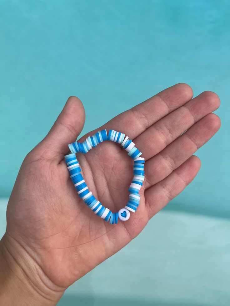 A blue and white bracelet with a heart bead! Blue Preppy Bracelets, Blue Evil Eye Bracelet With Round Beads, Blue Heart Charm Jewelry For Friendship, Blue Bracelets With Heart Charm And Round Beads, Blue Heart Beaded Bracelets For Beach, Blue Heart Beads Bracelets For Beach, Blue Heart And Round Beads Bracelet, Blue Beaded Bracelets With Heart Beads For Beach, Blue Beaded Heart Bracelet