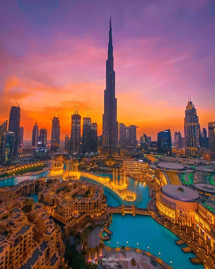 the city skyline is lit up at night with skyscrapers and buildings in the background