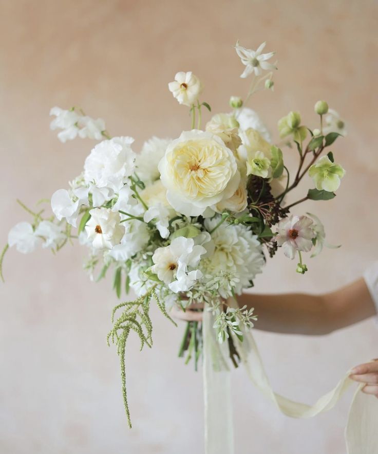 a woman holding a bouquet of white and yellow flowers