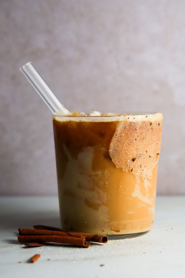 an iced drink with cinnamon on the side and a straw sticking out of it's top