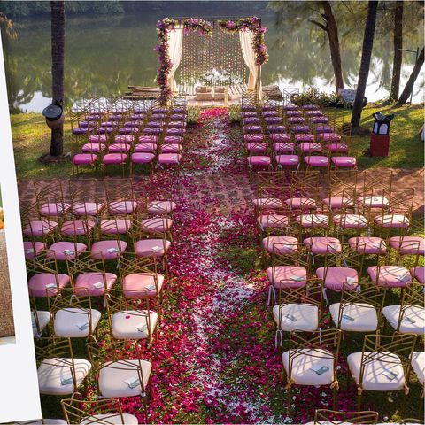 an outdoor ceremony setup with pink and white flowers on the ground, chairs are set up in rows