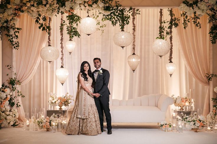 a man and woman standing in front of a white couch with floral decorations on it