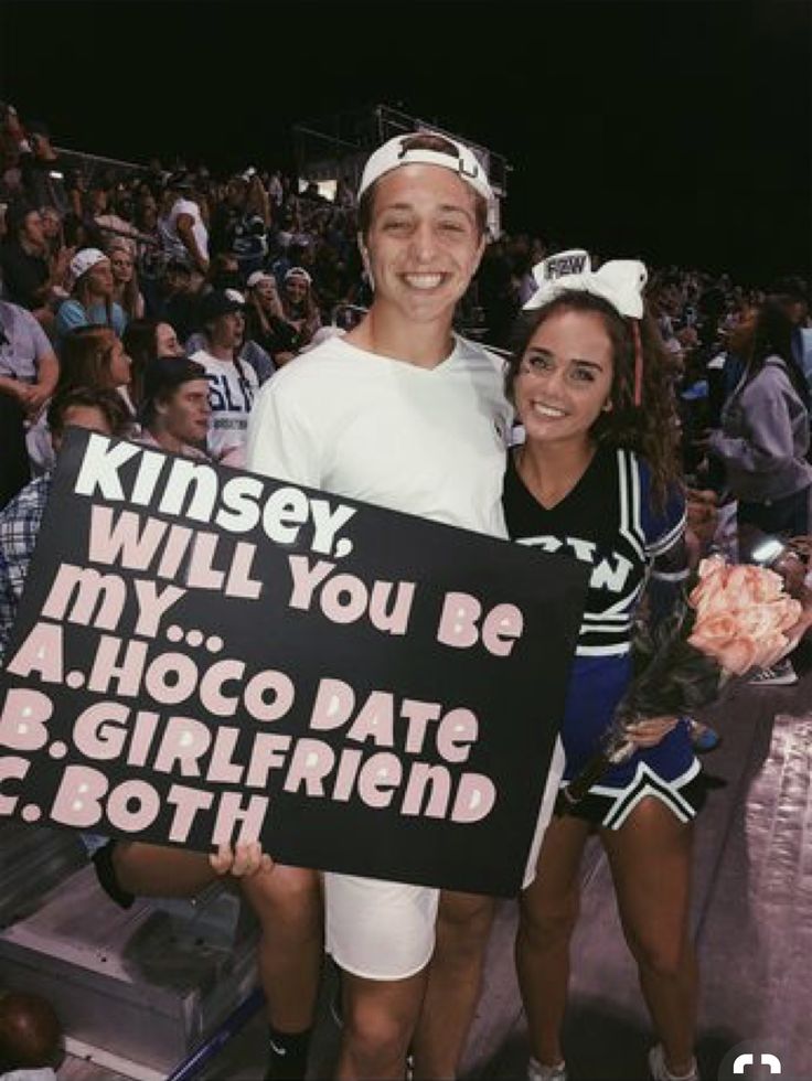 two people standing next to each other holding a sign