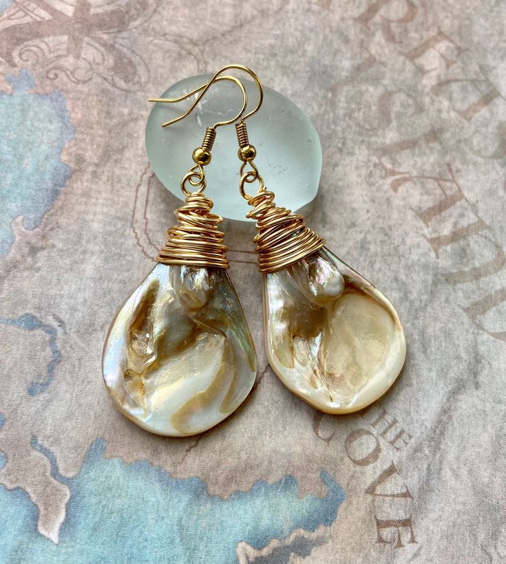 These teardrop shells are cream colored and iridescent with light brown accents. They are very playful with the light and are always changing! I wrapped them in non tarnish gold colored wire. The hooks are 18k gold plated brass. They are nickel free. Lever back hooks are available upon request. Dress them up for an evening out in your favorite dress, or dress em down with a pair of blue jeans. You can't go wrong with this simple and classy design. They also make a wonderful gift for the beach lo Pebble Jewelry, Beach Jewellery, Neutral Earrings, Coastal Jewelry, Stamped Earrings, Earrings Beach, Whimsical Jewelry, Elephant Earrings, Mother Of Pearl Jewelry