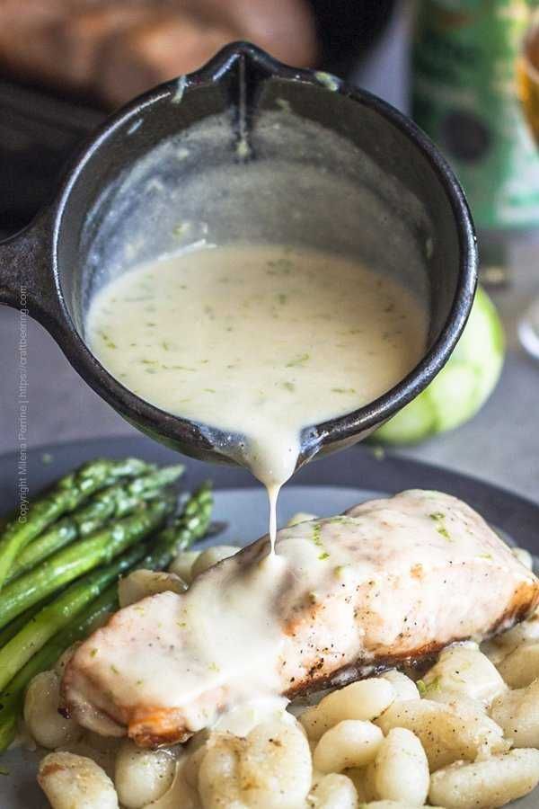 a person pouring sauce on some food with asparagus and broccoli in the foreground