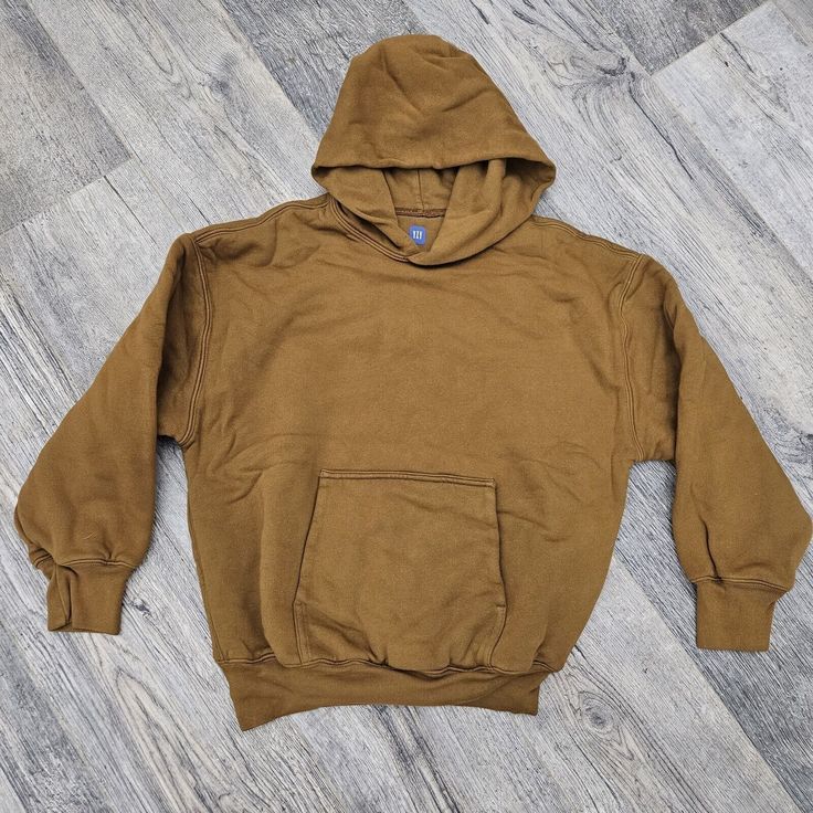 This Gap Hoodie In Khaki Brown Is A Must-Have For Any Fashion-Forward Young Boy. Designed By Yeezy Kanye, This Pullover Style Hoodie Is Authentic And Brand New Without Tags. It Comes In Size L And Is Perfect For Boys Who Love Comfortable And Stylish Clothing. The Brown Color Is Perfect For Any Occasion And The Hoodie Is Suitable For Any Casual Outing. Get This Hoodie Now And Elevate Your Child's Wardrobe Today! Khaki Hoodie With Kangaroo Pocket For Winter, Gap Hooded Hoodie For Fall, Gap Sweatshirt With Adjustable Hood For Fall, Solid Color Streetwear Tops With Kangaroo Pocket, Solid Tops With Kangaroo Pocket For Streetwear, Solid Color Tops With Kangaroo Pocket For Streetwear, Winter Khaki Sweatshirt For Streetwear, Sporty Gap Hoodie For Fall, Gap Hoodie With Ribbed Cuffs For Streetwear