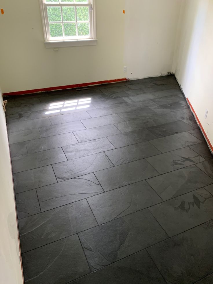 an empty room with black tile flooring and white walls