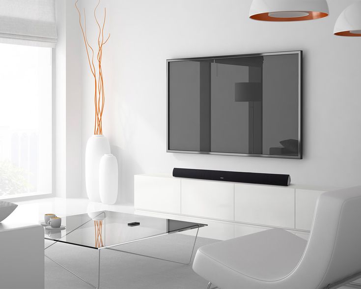 a living room with white furniture and a flat screen tv mounted on the wall above a glass coffee table