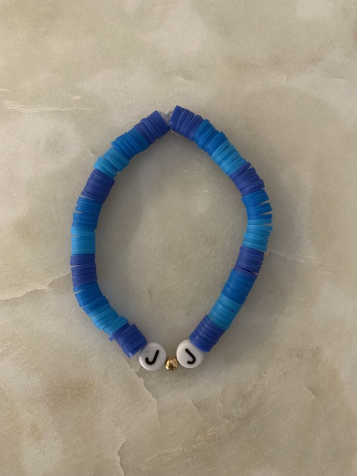 a blue and white beaded bracelet with the word u on it's end