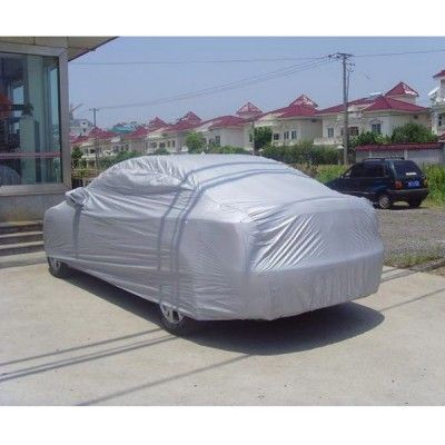 a car covered in a white sheet parked on the side of a road next to some houses