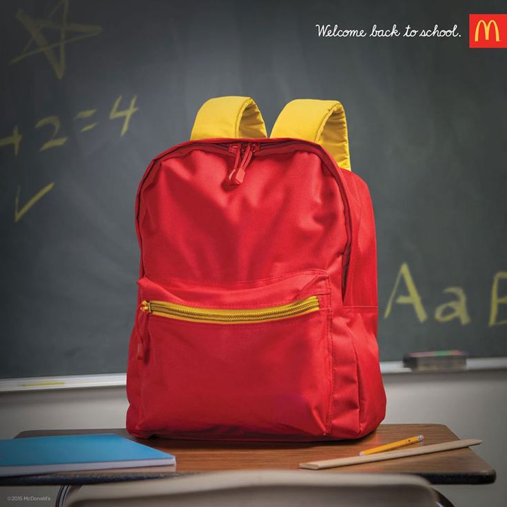 a red backpack sitting on top of a desk next to a chalkboard with writing on it