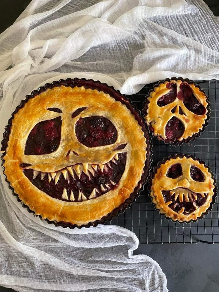 three pies with faces carved into them on a cooling rack