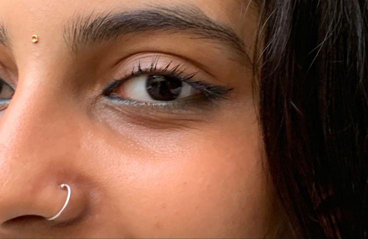 a close up of a woman's face with nose piercings on her nose