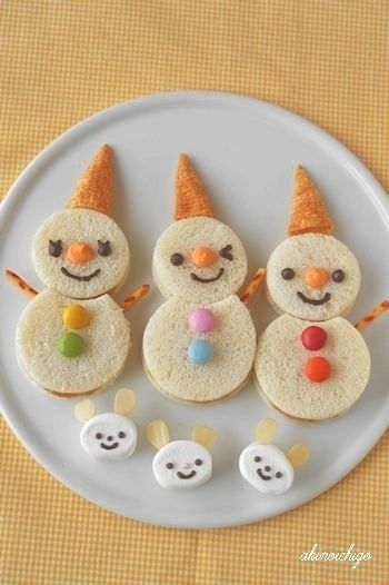 three snowmen are made out of bread on a plate with candy eyes and noses