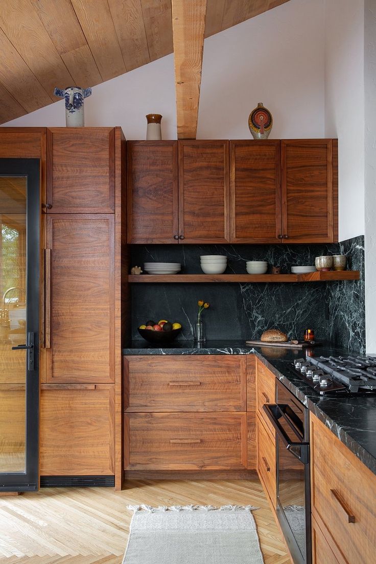 a kitchen with wooden cabinets and black counter tops, along with a rug on the floor