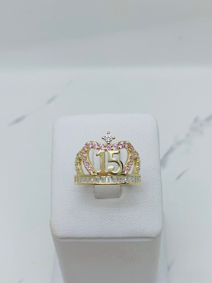 14k gold ring sweet 15 quinceañera crown    ❤️ Fine jewelry  ❤️ Size 8 ❤️ 100% 14k Yellow Gold with white and pink cubic zirconia  ❤️ Includes a box  Check out my other jewelry  ❤️ Anillo de quinceañera de 14k de oro sólido  ❤️ Corona de Quince años ❤️ Joyeria fina  ❤️ Esta sortija es tamaño 8 ❤️ Incluye Cajita ♥️ Piedra blanca y rosado en oro dorado   Vea mi página para ver más joyas SKU 042944 15 Rings Quinceanera Emerald Green, Gold Quince Ring, Pink Princess Jewelry For Wedding, Rose Gold Crown Design Jewelry For Anniversary, Pink Crown-shaped Wedding Jewelry, Personalized Yellow Gold Jewelry For Sweet 16, Princess Crown Jewelry For Anniversary, Quince Rings Gold, Quinceanera Rings