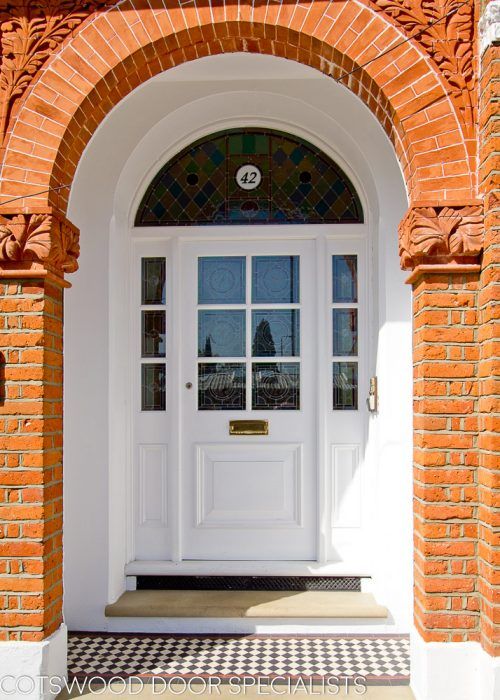 a white front door with black and white checkerboard flooring on the outside