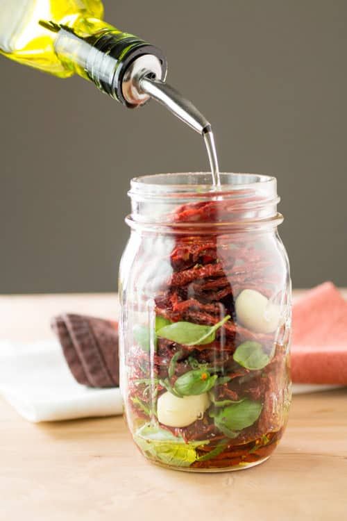 someone is pouring something into a jar filled with food