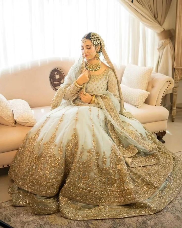 a woman sitting on top of a couch wearing a wedding dress with gold sequins