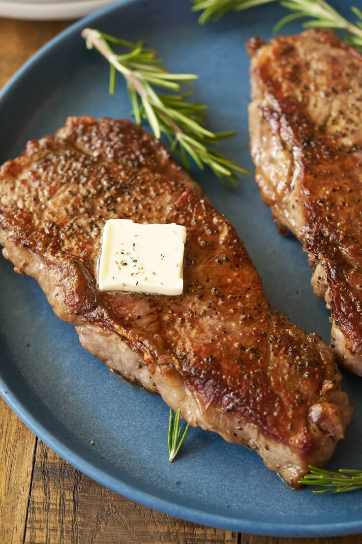 two steaks on a plate with butter and rosemary