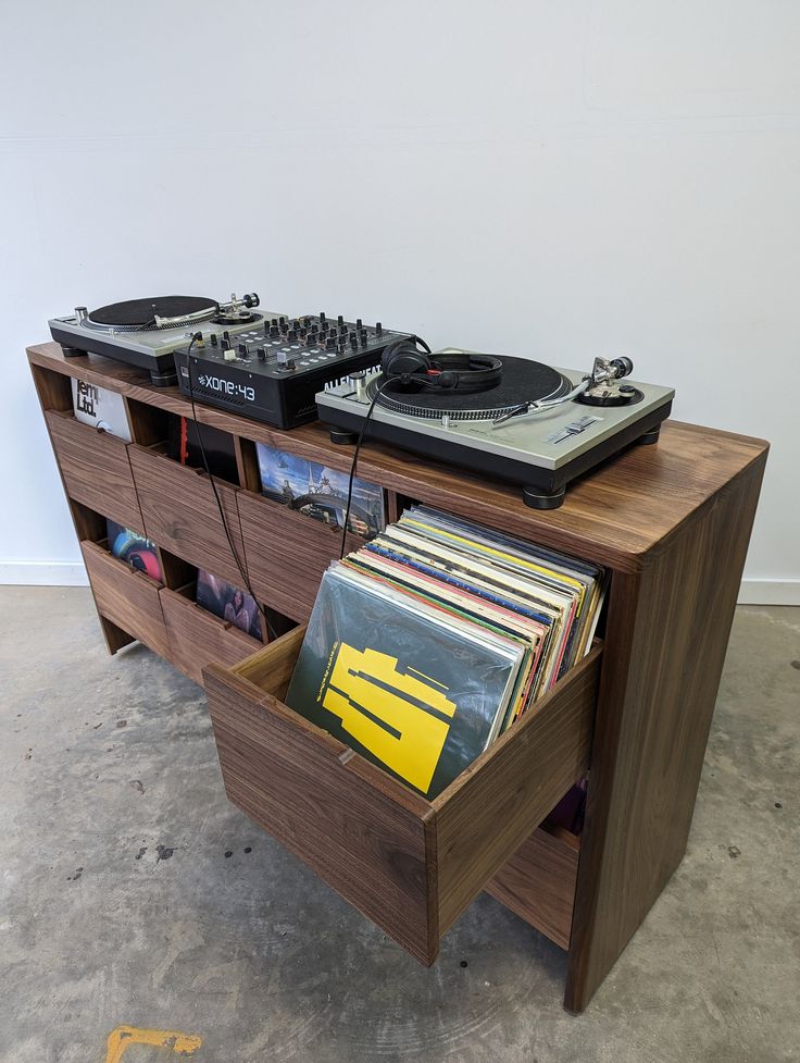 a record player and dj equipment sit on top of a wooden cabinet