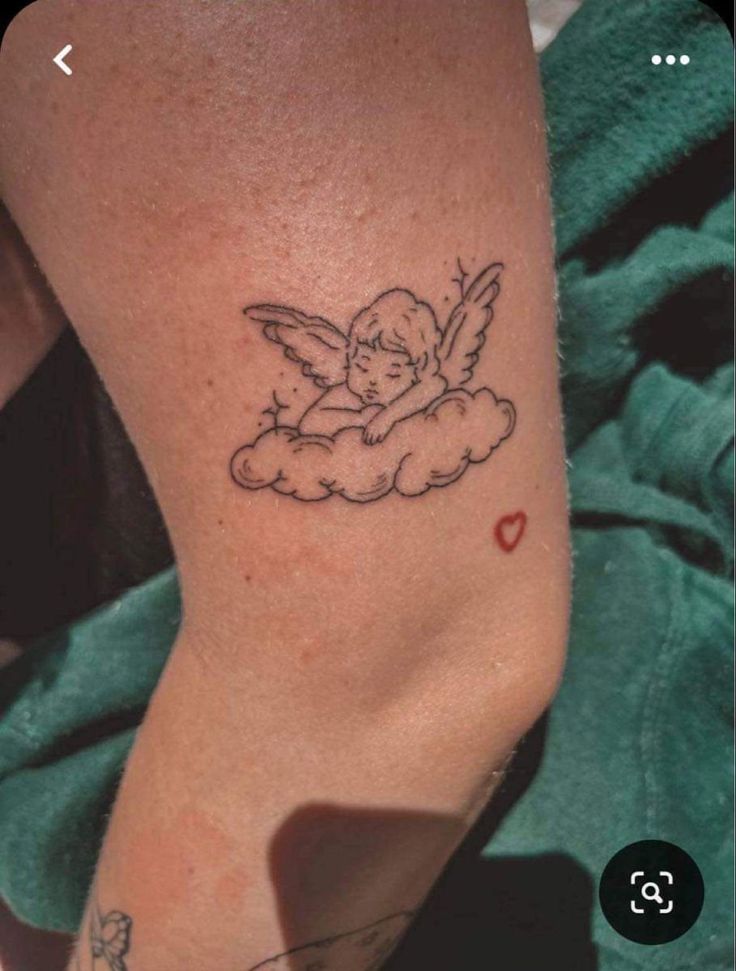 a small tattoo on the leg of a woman with an angel and heart in it