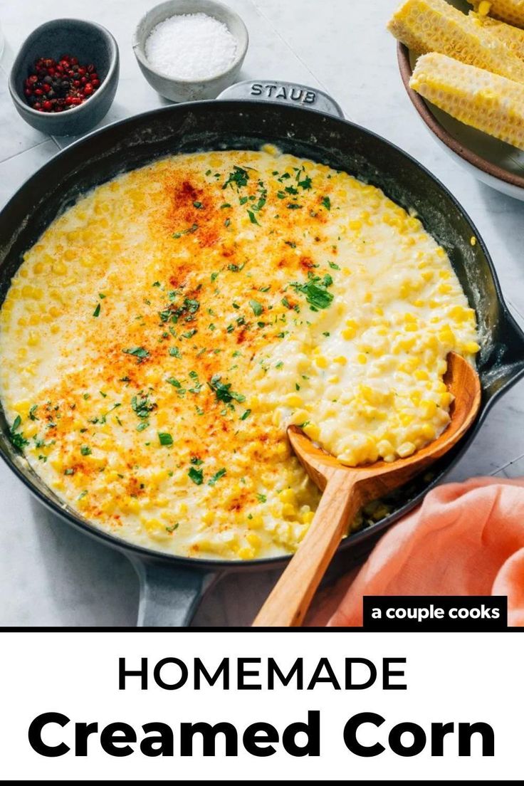 an omelet in a skillet with wooden spoons next to corn on the cob