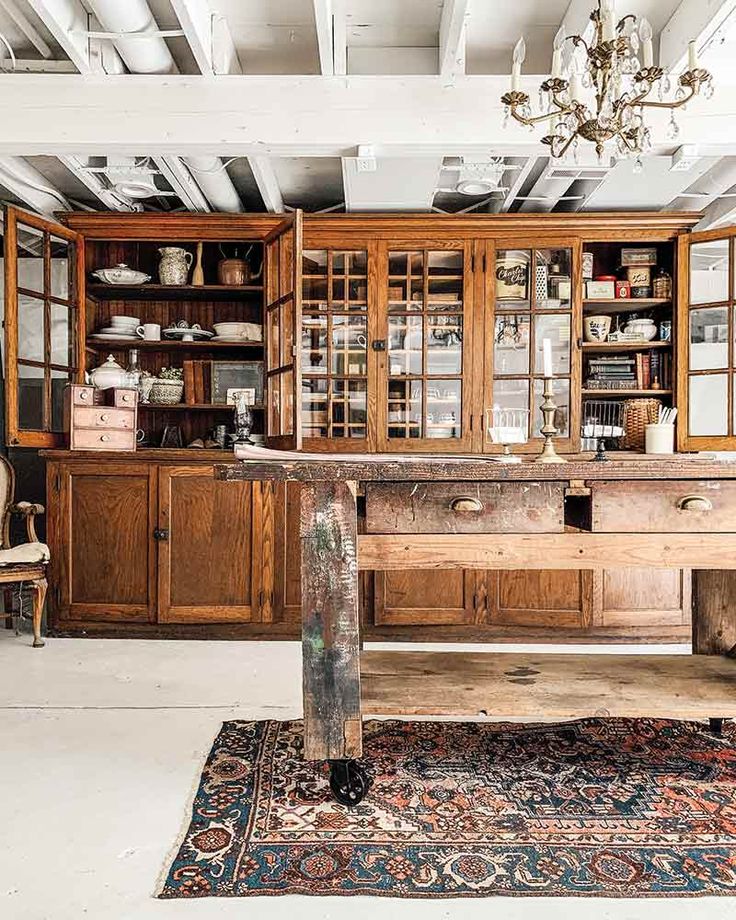 an old fashioned kitchen with lots of wooden cabinets and cupboards on the wall, along with a rug in front of it