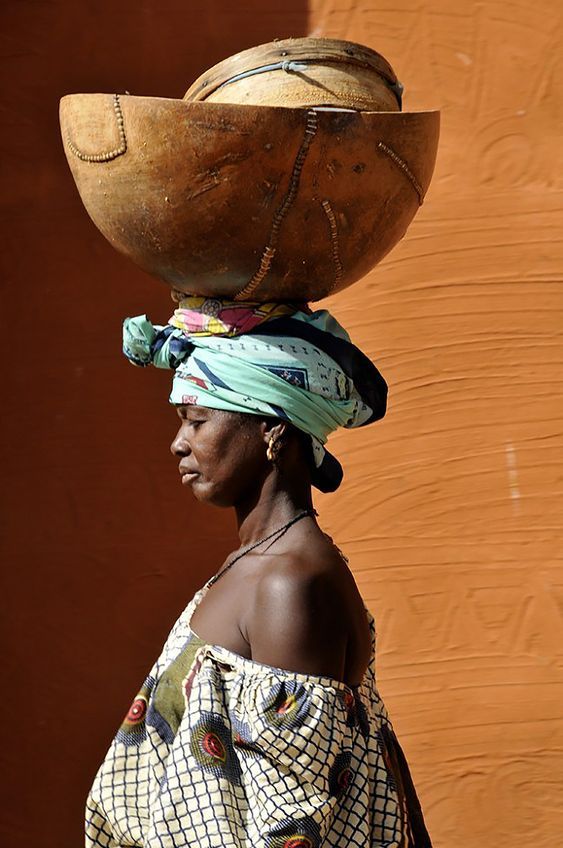 a woman with a large wooden bowl on her head