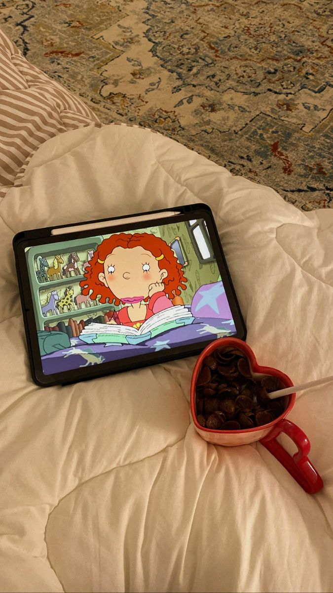 a tablet sitting on top of a bed next to a bowl of raisins