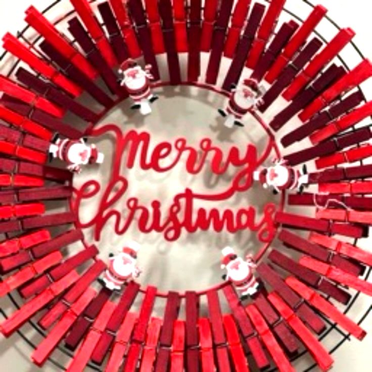 a christmas wreath made out of red plastic sticks with the words merry christmas written on it