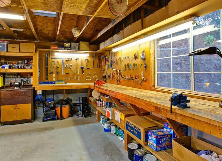 a garage filled with lots of tools and workbench on top of wooden shelves