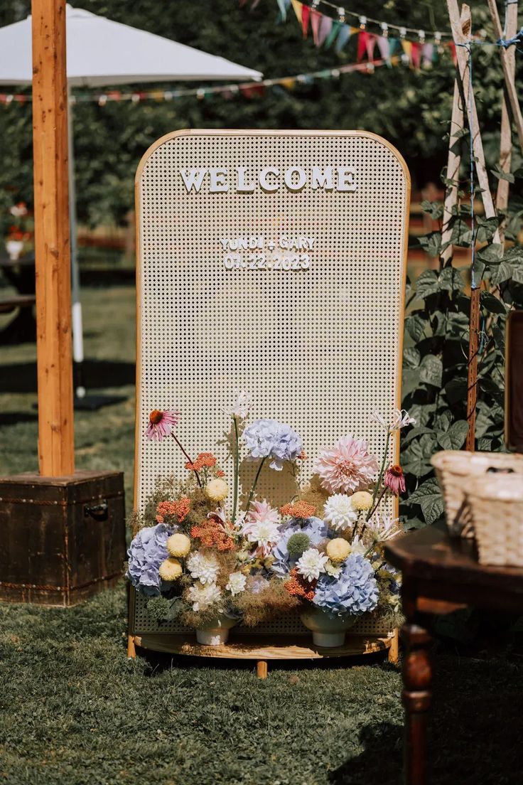 a welcome sign sitting on top of a lush green field next to a wooden barrel