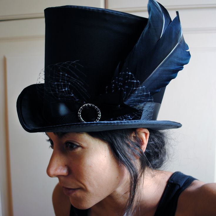 The Liza is a striking cabaret inspired full size top hat. It is covered with beautiful shiny black satin. It is decorated with black ribbon around the crown, black veil, half bow with black crystal buckle and two elegant black goose feathers. Also available as a medium size mini top hat: https://www.etsy.com/listing/256101614/victorian-witch-hatblack-mini-top?ref=shop_home_active_14 Need this TOP HAT in another color?Just send me a message to talk about a custom hat made just for you! This hat Fitted High Crown Costume Hats For Themed Events, Fitted High Crown Hats For Themed Events, Gothic Brimmed Hats For Themed Events, Gothic High Crown Costume Hat For Cosplay, Gothic High Crown Costume Hat, Black Gothic Hat For Costume, Black Gothic Hat For Cosplay, Fitted Brimmed Top Hat For Themed Events, Steampunk Top Hat With Curved Brim For Costume