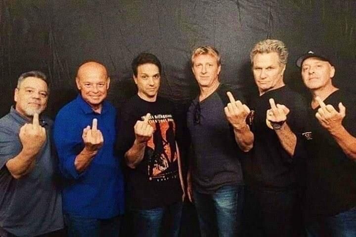 five men posing for the camera with their fingers in the shape of two peace signs