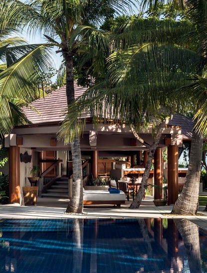 the pool is surrounded by palm trees and lounge chairs, which are set up on either side