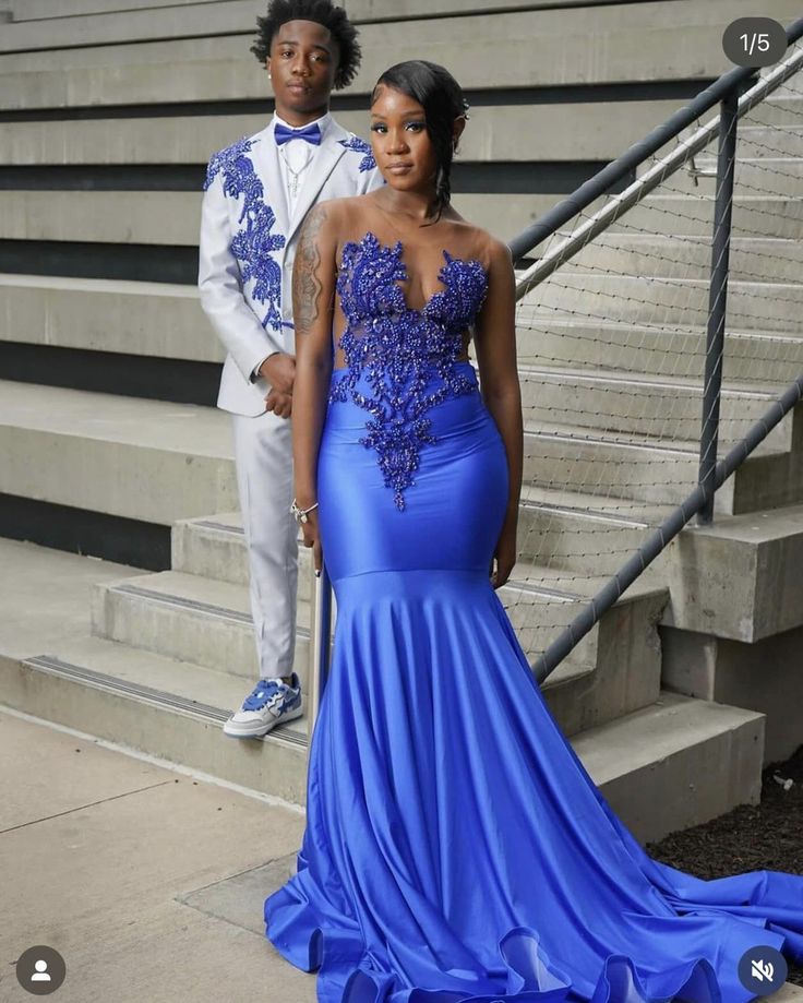 a woman in a blue dress standing next to a man