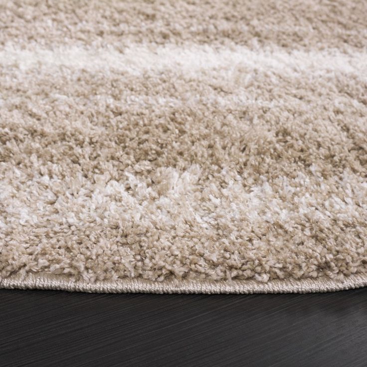 an area rug on a wooden floor with white and beige colors in the middle, closeup