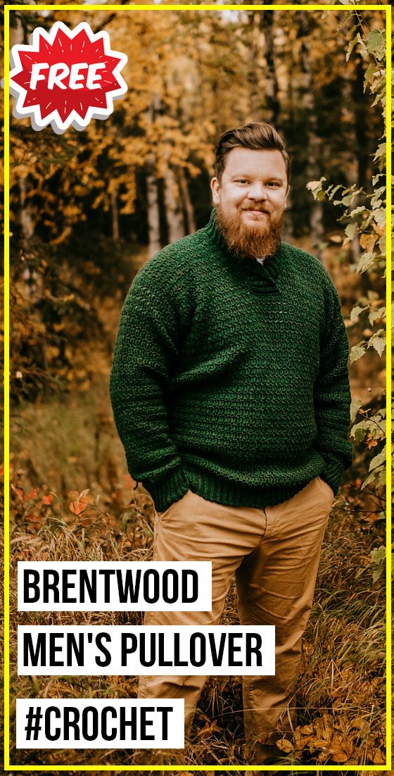 a man with a beard wearing a green sweater and khaki pants standing in front of trees