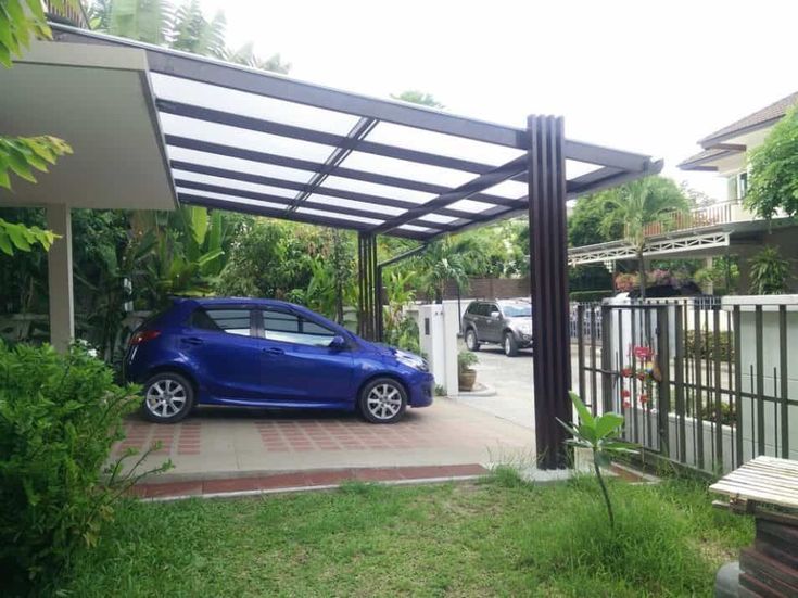 a small blue car parked in front of a house with a pergolated roof